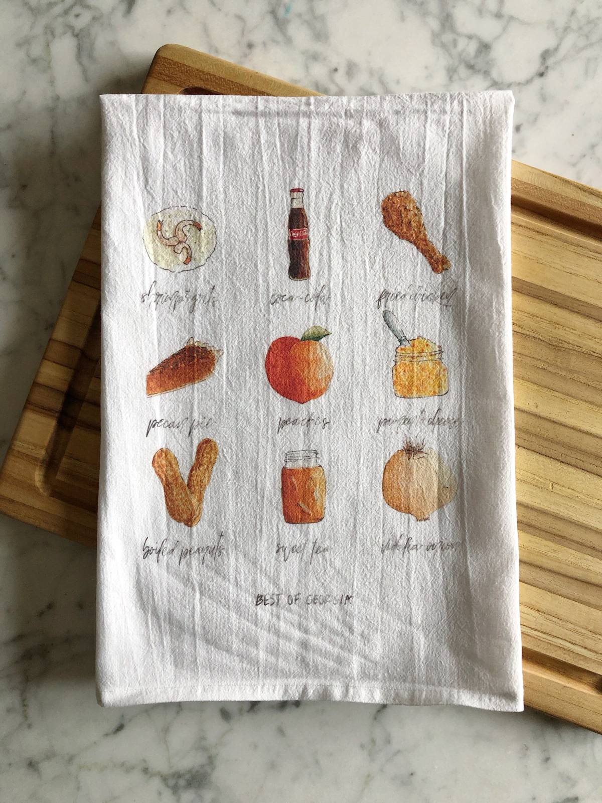 A white tea towel displaying 9 popular types of foods and drinks from the state of Georgia