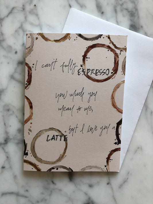 A tan card with an outline of watercolor coffee ring stains and the phrase "I can't fully espresso how much you mean to me, but I love you a latte"