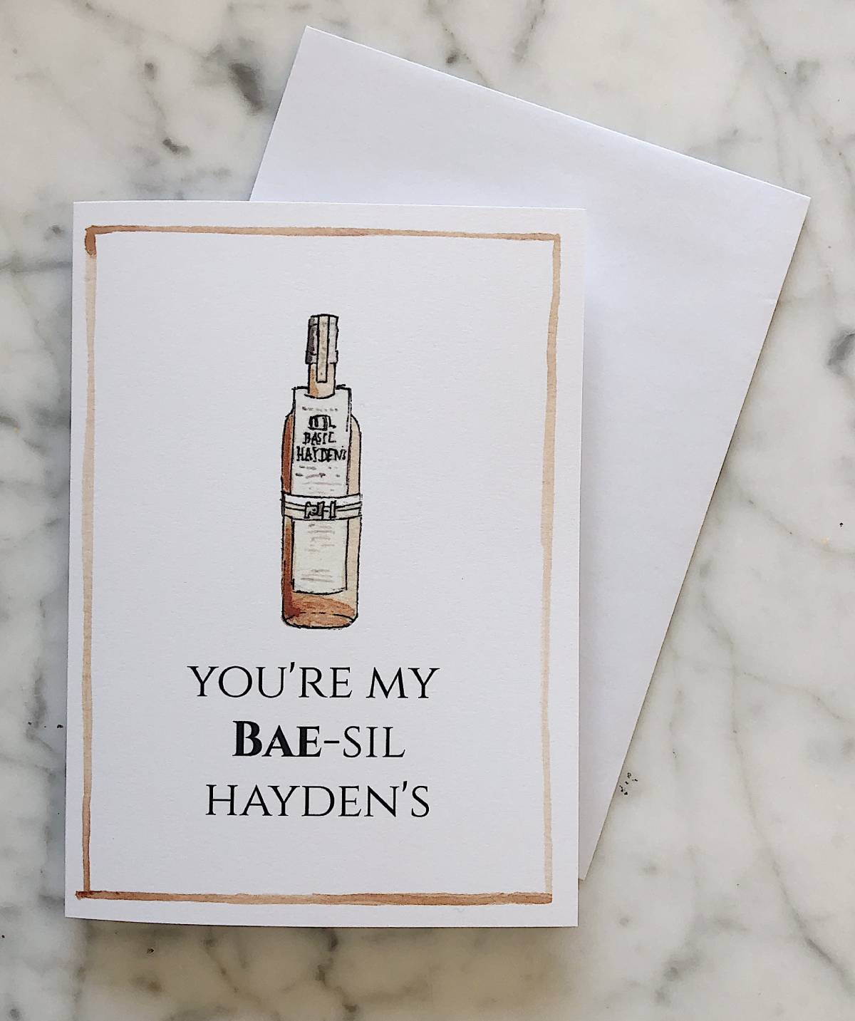A Valentine's Day card with a white background and brown outline showing a watercolor illustration of Basil Hayden's with the text "You're my BAE-sil Hayden's"