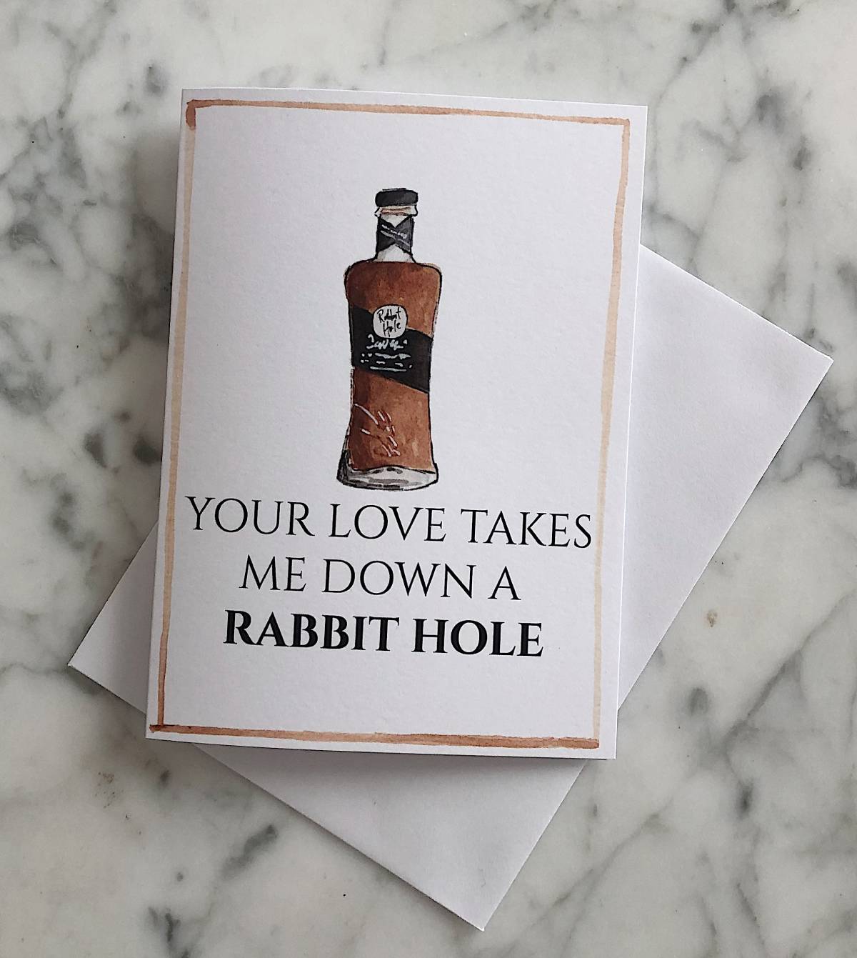 A white bourbon Valentine's Day card with an illustration of Rabbit Hole bourbon and the text "your love takes me down a rabbit hole"