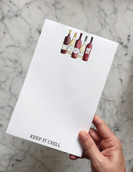 A fun wine notepad that has a white background with 5 different bottles of wine at the top - 3 red and 2 white - and the phrase "Keep It Chill" on the bottom of the pad. 